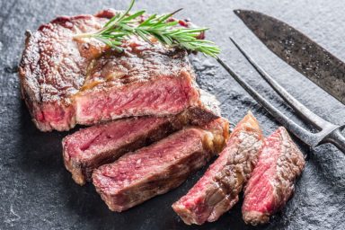 A cooked steak, cut up and served on a plate.